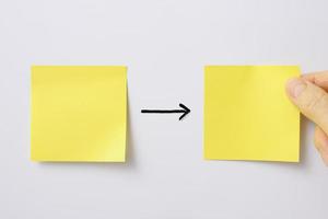 Two blank yellow sticky note with finger on a whiteboard
