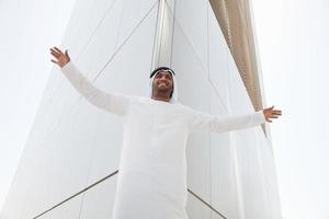 Middle eastern man outside dubai building with arms open