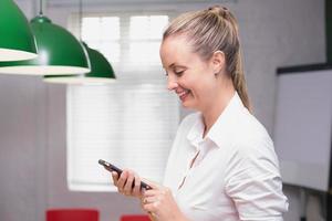 Blonde smiling businesswoman using smartphone photo