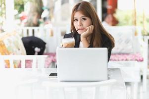 Asia joven mujer de negocios sentado en la cafetería con laptop