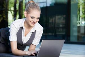 Young businesswoman working on laptop outdoors