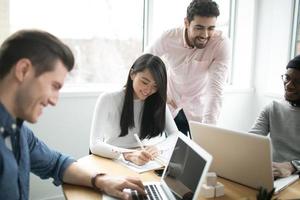 jóvenes profesionales trabajando en computadoras portátiles en una oficina foto