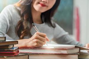 Un joven estudiante asiático haciendo los deberes en una biblioteca foto