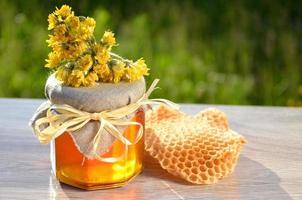jar of honey piece of honeycomb and wild flowers photo