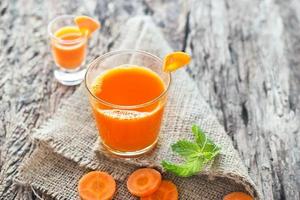 Fresh carrot juice on sack and wooden background photo