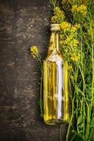 Bottle of Rape oil on rustic wooden background, top view photo