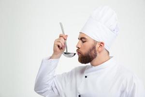 Chef cook holding a soup ladle and smelling it