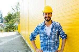 adult worker with helmet on yellow wall photo