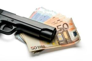 Montón de billetes en euros con una pistola