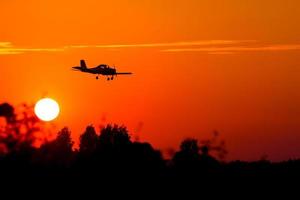 silueta de pequeño avión contra el telón de fondo de la puesta del sol foto