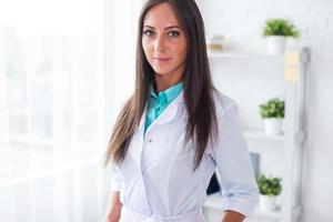 Portrait of young woman doctor with white coat standing in photo