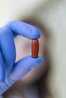 mujer sosteniendo cápsulas de píldora roja