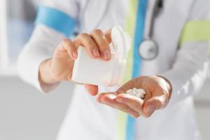 Doctor vertiendo píldoras de medicina en la mano foto