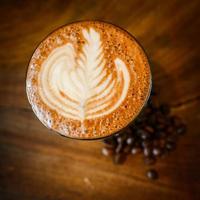 Latte Art y granos de café en madera foto