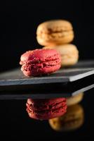 Pila de coloridos macarons franceses en pizarra con fondo negro foto