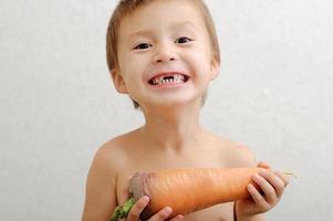 niño feliz sin dientes con zanahoria