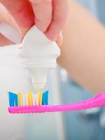 manos de mujer poniendo pasta de dientes en el cepillo de dientes foto