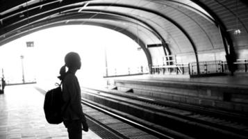 Silueta turista mochilero chica esperando el tren en el foto