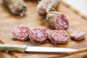 Italian salami slices on cutting board with kitchen knife photo