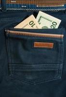 dólares estadounidenses en el bolsillo trasero de los jeans foto