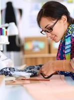 Diseñador de moda cortando textiles junto a una máquina de coser foto