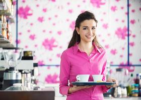 joven camarera sonriente sirviendo café en el bar foto