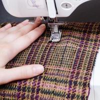 Mano y pie de la máquina de coser sobre tela de lana