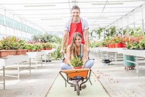 sellers couple have fun pushing the wheelbarrow in a greenhouse photo