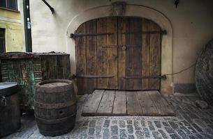 Antigua puerta de madera oxidada con barril como telón de fondo