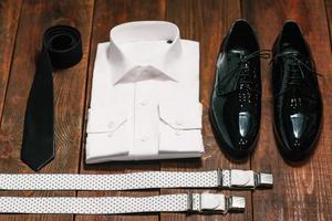 corbata negra, zapatos de charol, tirantes, una camisa blanca