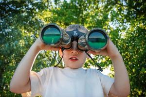 niño pequeño mirando a través de binoculares foto