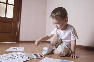 Boy Painting With Watercolors And Paintbrush photo