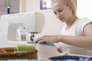 Mujer que trabaja con la máquina de coser en casa foto