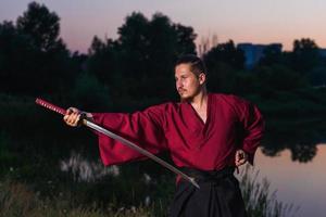 Hombre en uniforme de ropa japonesa samurai étnico con espada katana