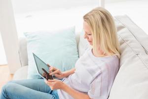 Mujer usando tableta digital mientras está sentado en el sofá foto