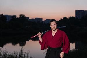 Hombre en uniforme de ropa japonesa samurai étnico con espada katana
