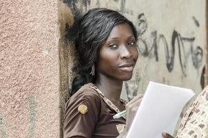 símbolo de aprendizaje: sonriente joven empresaria africana estudiando escritura trabajando