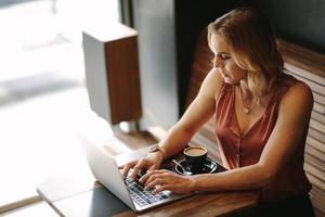 Mujer trabajando en una computadora portátil en una cafetería.