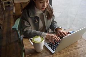 mujer con café matcha usando laptop