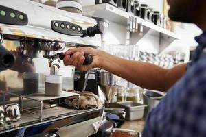 Joven barista masculino preparando café en un café, cerrar
