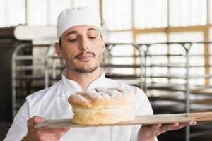 panadero que huele un pan recién horneado foto
