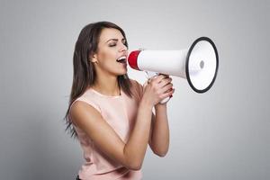 Young beautiful woman screaming by megaphone photo