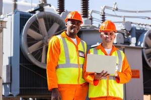 electrical engineers with laptop in front of transformer photo