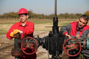 Two Skilled Oil and Gas Engineers in Action at Oil Well photo