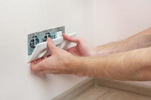 The hands of an electrician installing a wall power socket photo