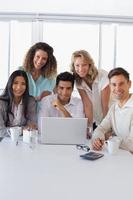 equipo de negocios informal sonriente que tiene una reunión usando la computadora portátil foto