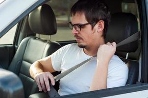 Conductor europeo masculino está usando el cinturón de seguridad en un automóvil