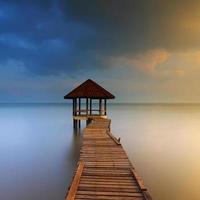 Sunset of wooden landing with pavilion in the sea photo