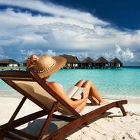mujer joven leyendo un libro en la playa