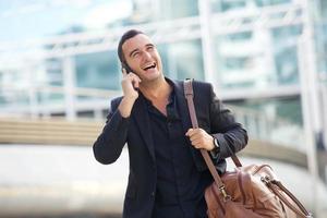 hombre feliz caminando en la ciudad con teléfono móvil y bolso